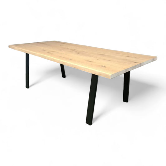 Seitenansicht des Holztisches Solana mit massiver Wildeiche Tischplatte und schrägen Stahlbeinen.